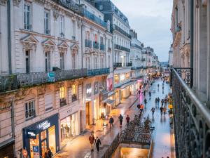 people walking down a street in a city at night at Le Voluptueux - Sauna - Jacuzzi - Centre-Ville in Angers