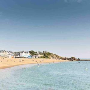 una playa con un grupo de personas en el agua en Saint Nazaire 4 chbres 15min de la plage à Saint Marc KER LOT MARC, en Saint-Nazaire