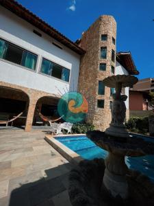a fountain in front of a building with a pool at Pousada Guaruondas in Guarujá