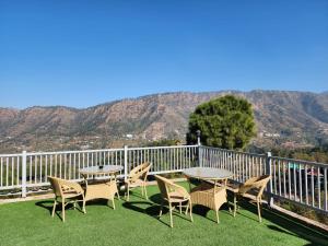 a patio with tables and chairs with mountains in the background at kasauli Countryside inn by Kasauli Vista in Kasauli