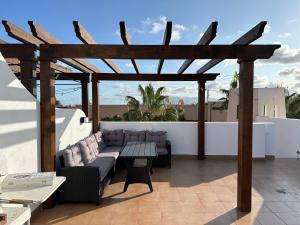 ベラにあるAtico duplex con piscina privada, solárium y barbacoaのパティオ(ソファ、木製パーゴラ付)