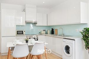 a kitchen with white cabinets and a table and chairs at Bright and Modern 2-bed Home in Newark on-Trent by Renzo, Free Parking, Sleeps 5! in Newark upon Trent