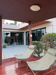 two chairs sitting on a deck in front of a house at Pool villa Phuket in Kata Beach