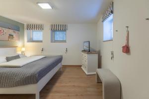 Un dormitorio con una cama, una cómoda y ventanas. en Ahoi, en Sankt Peter-Ording