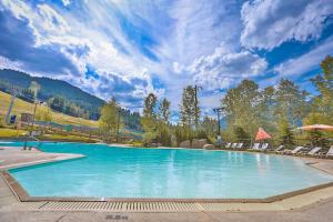 a large swimming pool with chairs and a mountain at Ravenwood Cabin by StayIn in Panorama