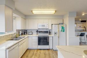 a kitchen with white cabinets and white appliances at Let the Good Times Roll in Lincoln City +14 photos