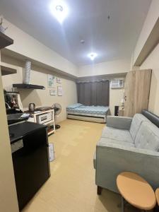 una sala de estar con un sofá y una cama en Cozy Studio in Ayala Avida CDO - Fast WIFINetflixTv, en Cagayan de Oro