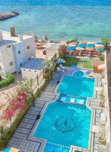 a resort with two pools and umbrellas and the ocean at Tiba Rose hurghada in Hurghada