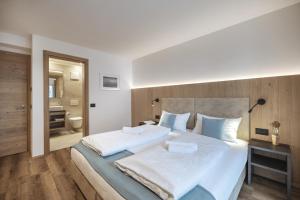 sypialnia z dużym białym łóżkiem i łazienką w obiekcie Apartment Villa Stefania w mieście Selva di Val Gardena