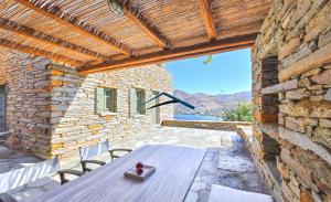 a patio with a wooden table and a stone wall at Otzia Sunrise Retreat in Otzias