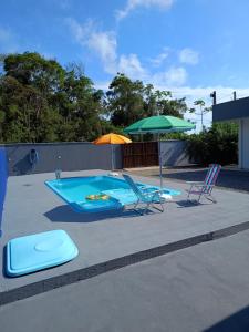 a swimming pool with two chairs and an umbrella at Casa com Piscina e ampla area de festas in Barra Velha
