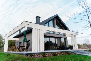 a house with columns on the side of it at Flora & Sauna Kamieńczyk Konwaliowa 8 in Błonie