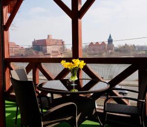 a table and chairs with a vase of flowers on a balcony at EdMar in Malbork