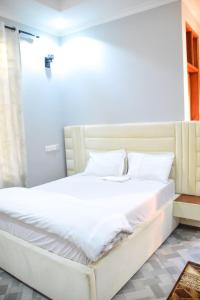 a bed with white sheets and pillows in a room at chamber 206 in Arusha