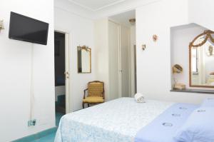 ein weißes Schlafzimmer mit einem Bett und einem Fernseher in der Unterkunft SEI A CAPRI in Capri