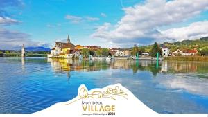 a boat in a body of water with a town at Bel appartement proche Annecy Aix-les-bains Genève in Seyssel