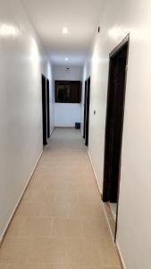 a hallway with white walls and a tile floor at Hôtel super marché in Mhamid