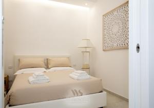 a white bedroom with a bed with towels on it at WHITE SOFIA - uno sguardo sul mare in Bari