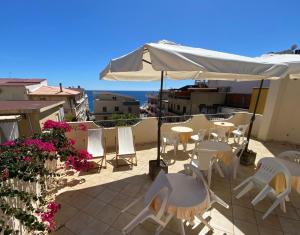 a patio with tables and chairs and an umbrella at Hotel Sylesia in Letojanni