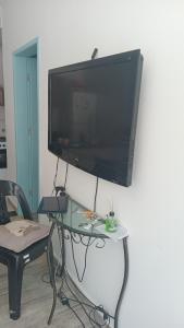 a television hanging on a wall with a glass table at CANTO DO PARAÍSO Praia RUÍNAS in Peruíbe