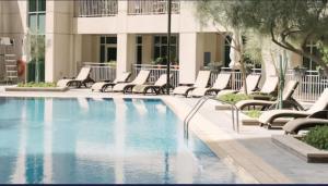 a swimming pool with lounge chairs next to a building at Luxury 2-bed Condo Full Burj Khalifa Lights View! in Dubai