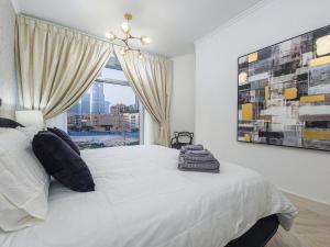 a bedroom with a large white bed with a window at Luxury 2-bed Condo Full Burj Khalifa Lights View! in Dubai +24 photos