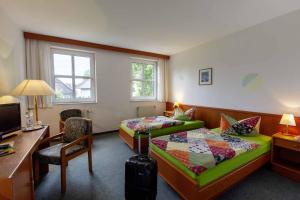 a hotel room with two beds and a desk at Landhotel Alter Weber in Cunewalde