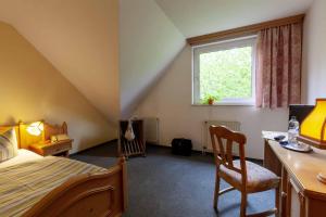 a bedroom with a bed and a desk and a window at Landhotel Alter Weber in Cunewalde +3 photos