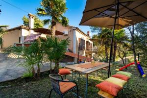 a table and chairs with an umbrella in front of a house at Apartments Carmen in Matulji