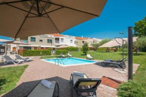 een terras met stoelen en een parasol en een zwembad bij MAJ - ANA - Luxury Family Apartments with Pool in Poreč