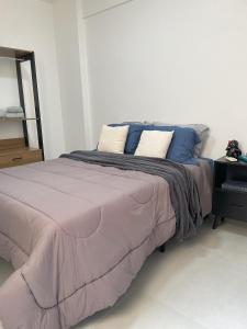 a bed with blue and white pillows on it at Ed Casablanca proximo a Av T63 shopping e parque in Goiânia
