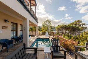 a balcony with chairs and a swimming pool at SEIA Dream offers stunning ocean views, sunny living spaces, plunge pool and terraces perfect for relaxing, Walk to Simons Town, Seaforth Beach, Boulders Beach penguins, high speed internet, smart TV and back up solar, ideal for families or remote work in Simonʼs Town