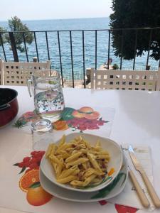 a plate of pasta on a table with a view of the ocean at Bethel House in Gardone Riviera