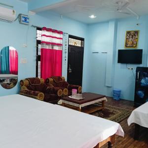 a room with a bed and a couch and a tv at Shri SeetaRam Home Stay Near Shri Ram Janmabhoomi Mandir Ayodhya in Ayodhya +3 photos