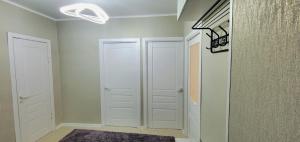 a hallway with white doors and a rug at Квартира уют in Karakol