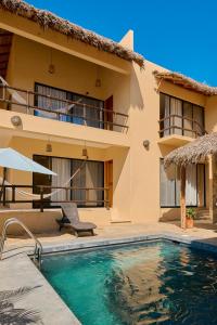a villa with a swimming pool in front of a house at Lya Beach House in Santa María Colotepec