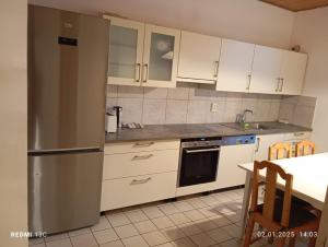 a kitchen with white cabinets and a stainless steel refrigerator at apartament N-R in Röthenbach an der Pegnitz