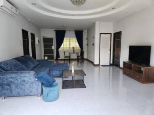 a living room with a blue couch and a tv at Baan Fah Chiangrai in Chiang Rai