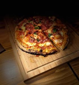 a pizza sitting on top of a wooden cutting board at La Bella Vita Agriturismo in Chiaramonte Gulfi