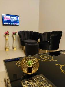 a living room with chairs and a table and a television at Private & Cozy 2-Bedroom Full Apartment for Families E11 Islamabad in Islamabad
