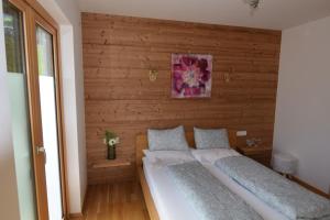 dwa łóżka w pokoju z drewnianą ścianą w obiekcie Koenigsjodler Lodge, Dienten, Mountain Resort w mieście Dienten am Hochkönig