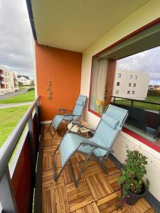 a balcony with two chairs and a window at Sentral og koselig leilighet in Haugesund