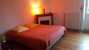 a bedroom with a bed with a light on the wall at Chambres d'hôtes et T2 dans écolieu arts, ride et autres activités in Saint-Pandelon