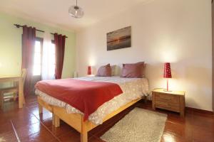 Un dormitorio con una cama grande con una manta roja. en Casa Papoila T1 com terraço, en Vila Nova de Milfontes
