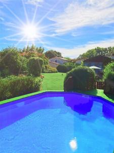 a blue swimming pool in a yard with the sun in the sky at Studio, aire de loisirs avec piscine in Marigny