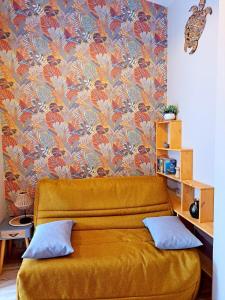 a yellow couch in a room with a floral wallpaper at Studio, aire de loisirs avec piscine in Marigny +12 photos