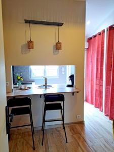 a kitchen with two bar stools and a sink at Studio, aire de loisirs avec piscine in Marigny
