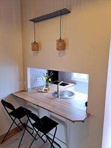 a kitchen with a counter with chairs and a sink at Studio, aire de loisirs avec piscine in Marigny