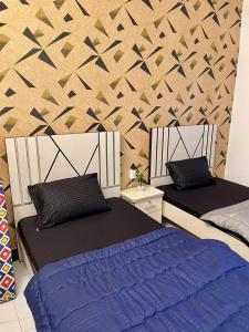 Comfortable 1 & 2 Bedroom Apartment in DHA by Virani في كراتشي: سريرين في غرفة بها جدار