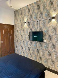 Comfortable 1 & 2 Bedroom Apartment in DHA by Virani في كراتشي: غرفة نوم بها سرير وتلفزيون على الحائط